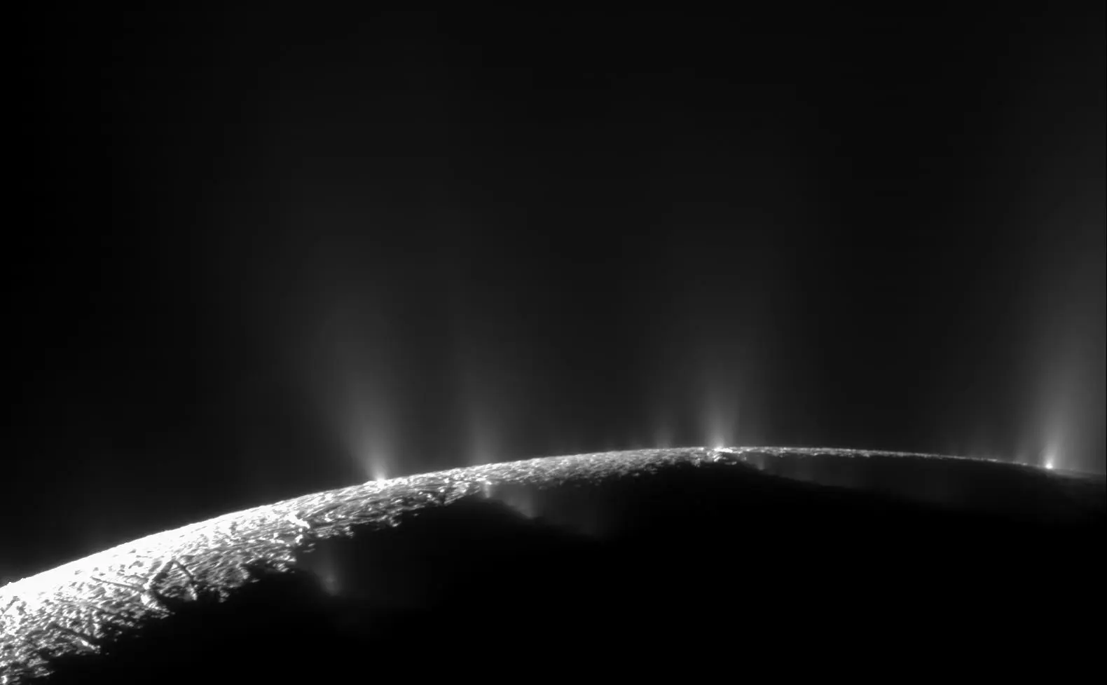 Backlit jets of ice rising from fractures along the limb of Enceladus
