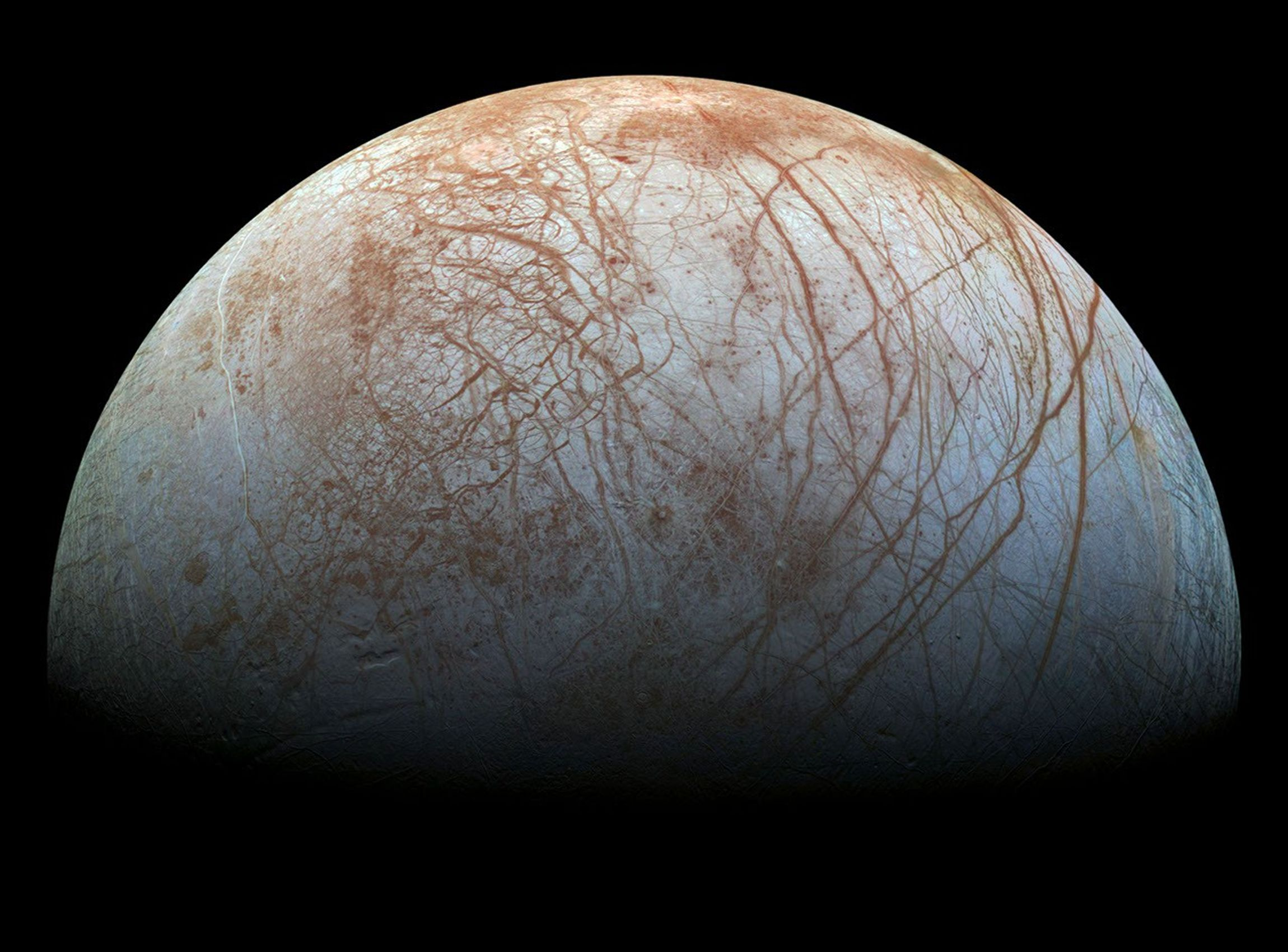 Europa's pale ice shell criss-crossed by long rust-coloured cracks