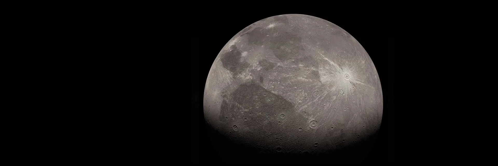 Ganymede, a grey cratered globe with bright ray craters and darker ancient terrain