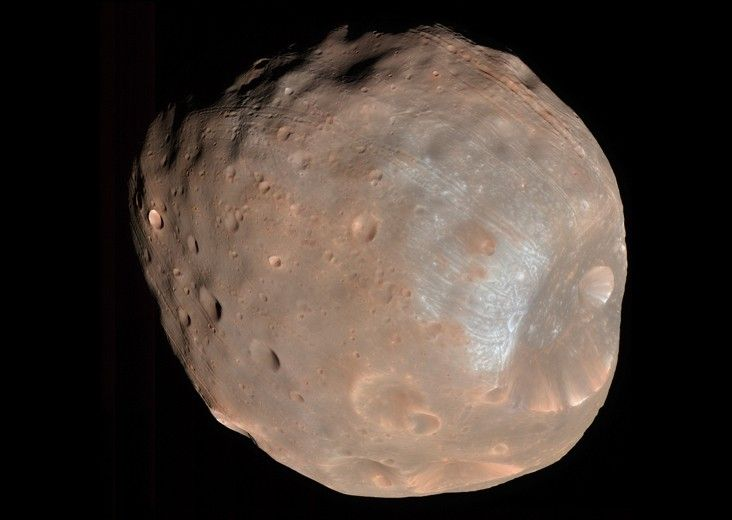 Phobos, a battered grey-pink lump with a large crater at one edge