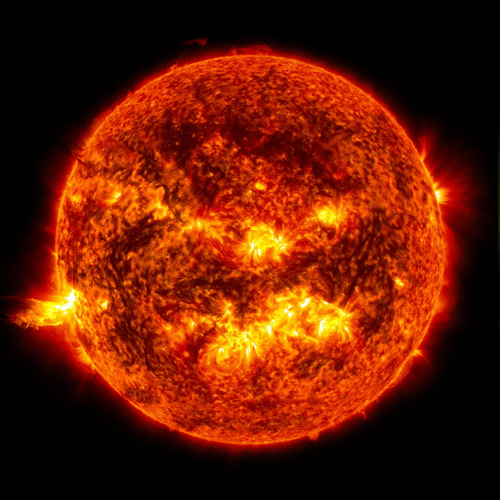 The Sun as a full orange disc, mottled with active regions and a flare at the limb